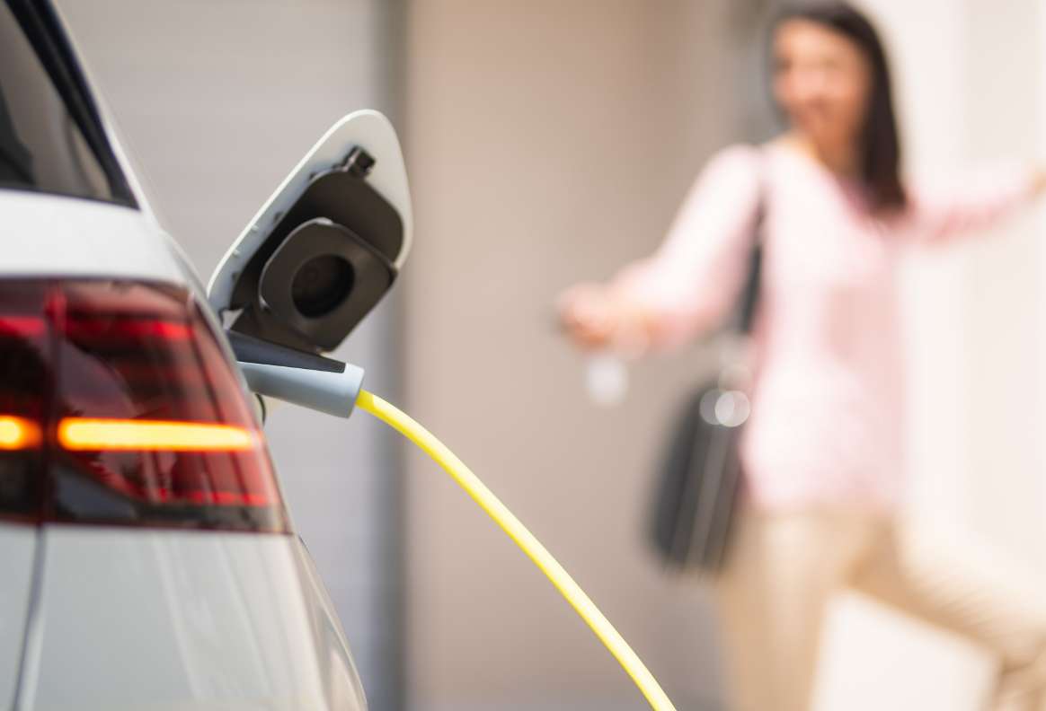 a person locking a car. the car is plugged into a charger.