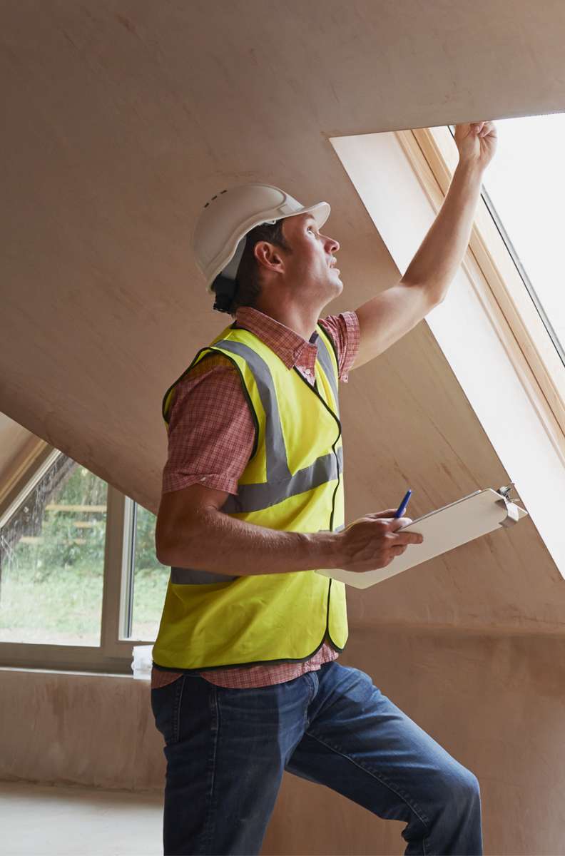 a person wearing a hi-vis jacket, holding a clipboard and checking a window