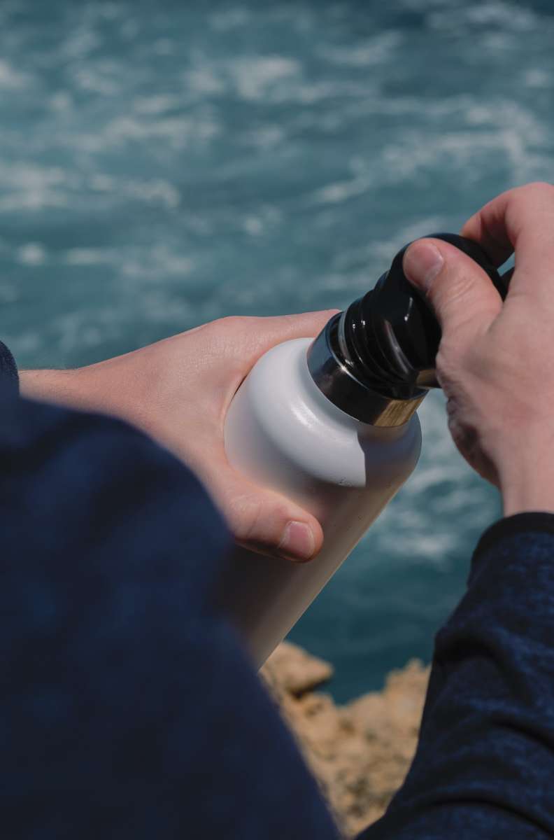 close up of a person's hands opening a reusable bottle