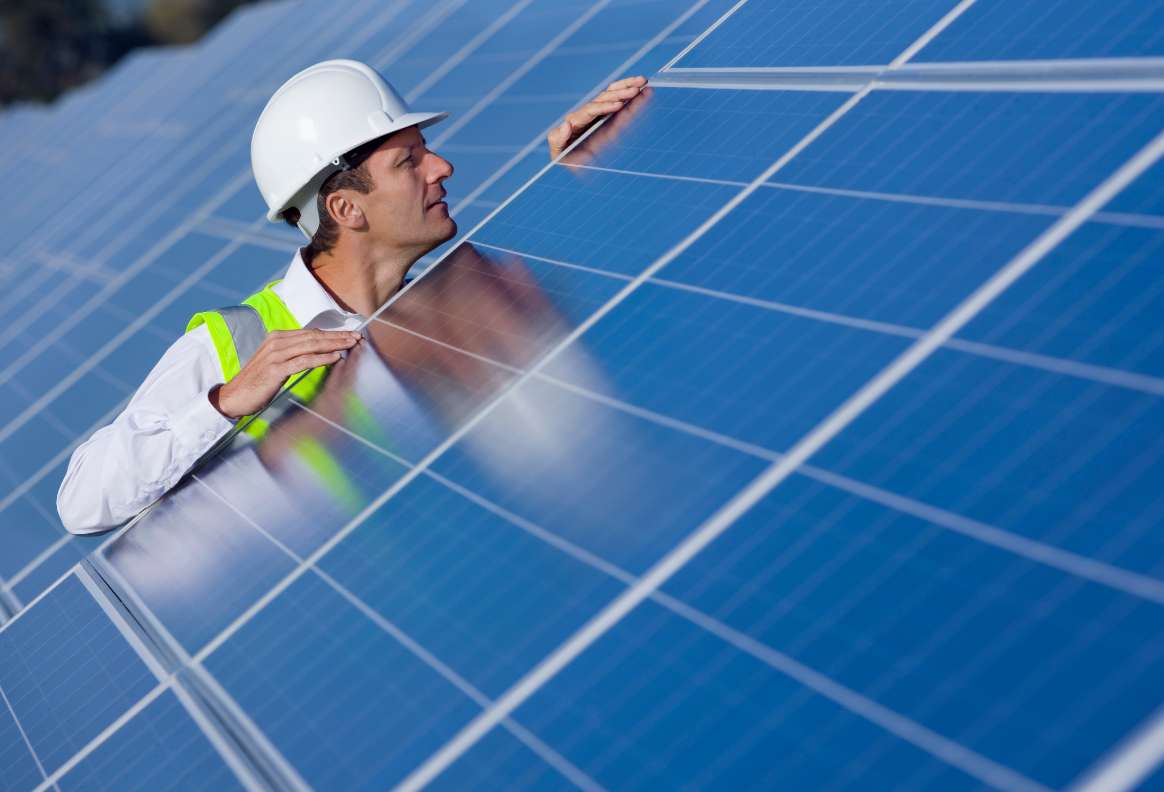 a person inspecting a large solar panel