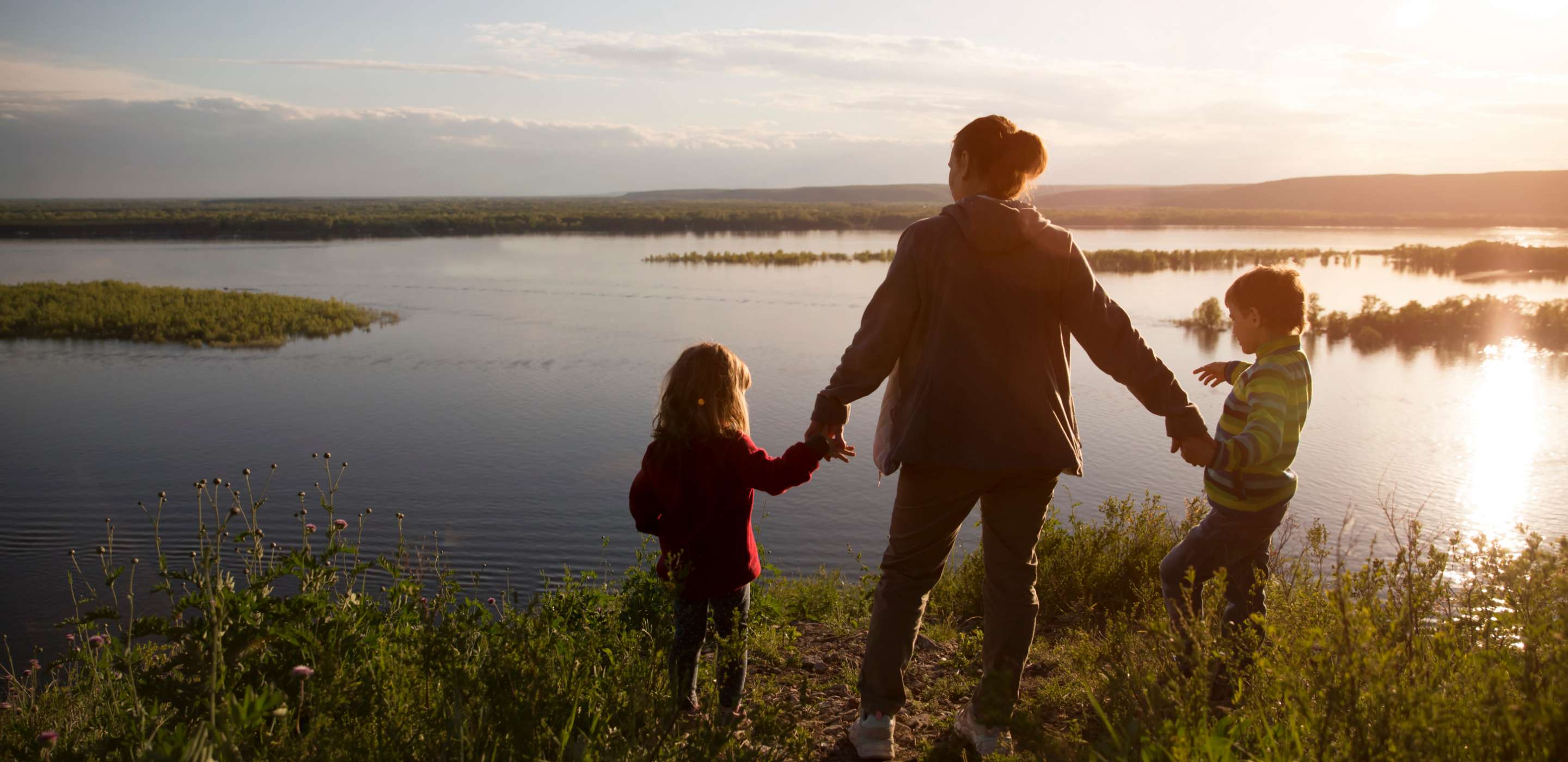 an adult and two children looking out over a lake